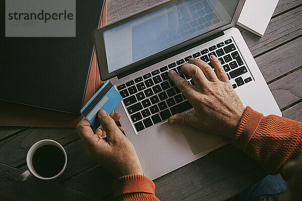 Senior Mann die Hände tun Online-Zahlung mit Kreditkarte durch Laptop zu Hause