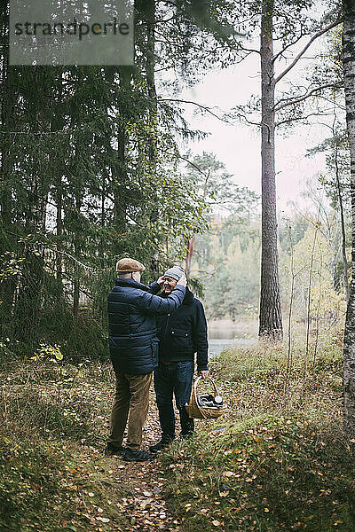 Homosexuelles Paar mit Picknickkorb stehend im Wald