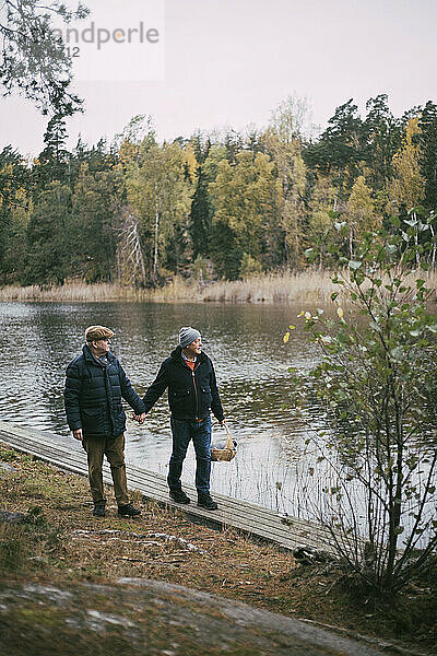 Homosexuelles Paar hält Hände beim Spaziergang am Flussufer