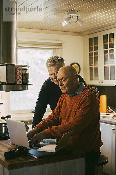 Homosexuelles Paar mit Laptop in der Küche zu Hause