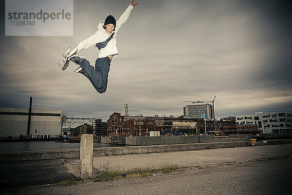 Mid erwachsenen Mann mit Skateboard springen gegen Himmel