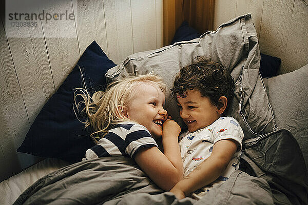 Lächelnde Geschwister schlafen nachts im Schlafzimmer