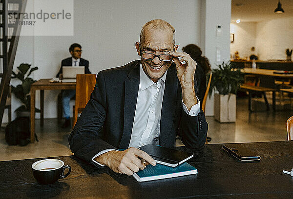 Porträt eines lächelnden männlichen Unternehmers mit Augen am Konferenztisch im Off