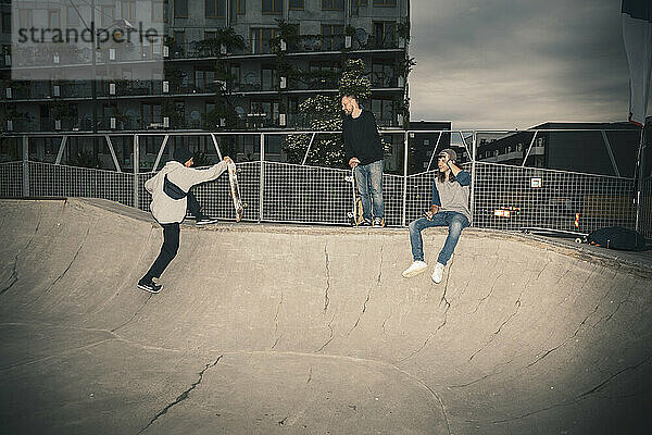 Männliche Freunde im Skateboardpark während der Dämmerung