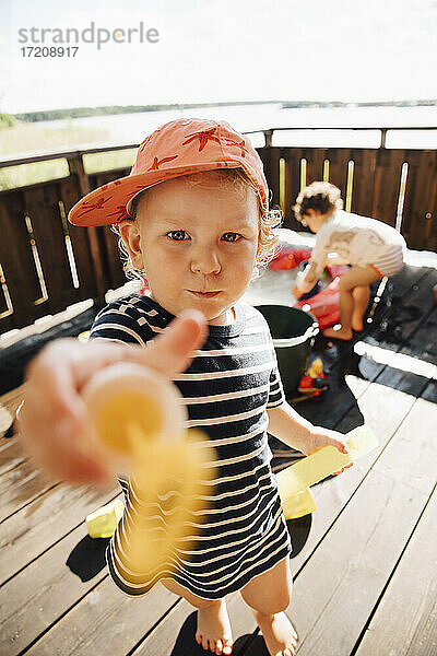 Porträt von niedlichen Jungen geben Spielzeug im Stehen im Freien während des sonnigen Tages
