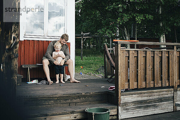 Vater schaut Sohn an  während er im Sommer auf einer Bank sitzt