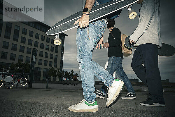 Männliche Skater auf dem Fußweg in der Dämmerung