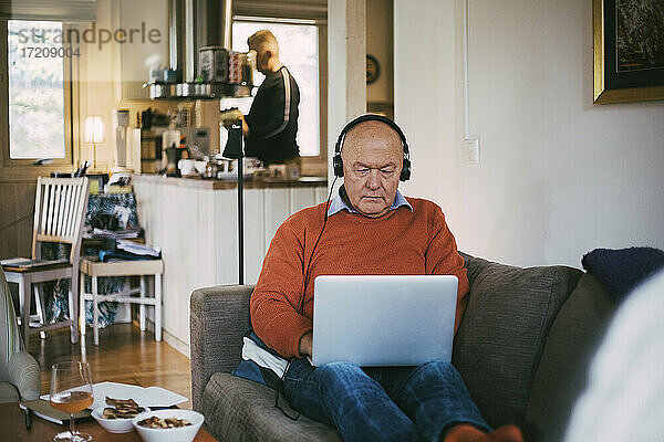 Älterer schwuler Mann  der einen Laptop benutzt  während er zu Hause sitzt