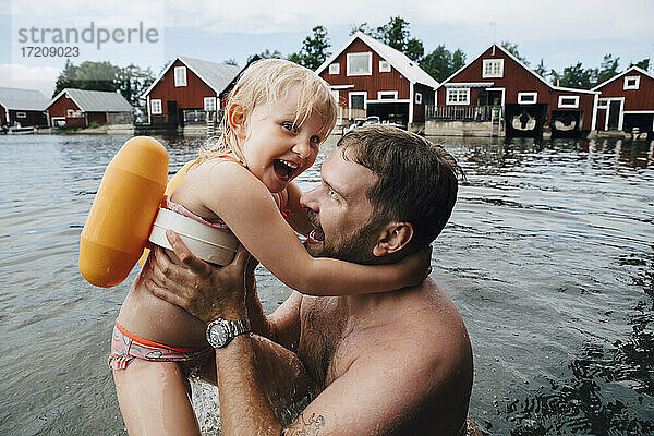Porträt der fröhlichen Tochter mit Vater im See während der Ferien