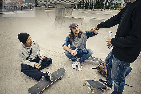 Männliche Freunde tun Faust bump auf Skateboard Park