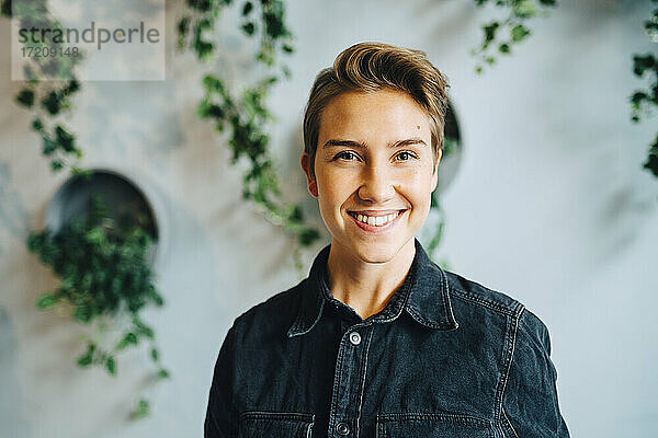 Porträt einer lächelnden Unternehmerin an der Wand im Büro