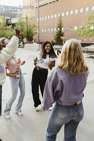 Glückliche weibliche Teenager Freunde tanzen im Skatepark