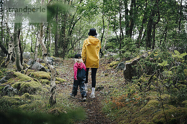 Rückansicht von Mutter und Tochter beim Spaziergang im Wald