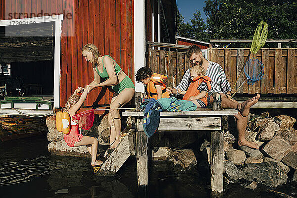 Vater mit Kindern auf dem Pier sitzend in den Sommerferien