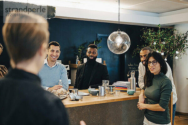 Lächelnde männliche und weibliche Kollegen  die am Tisch in einem kreativen Büro diskutieren