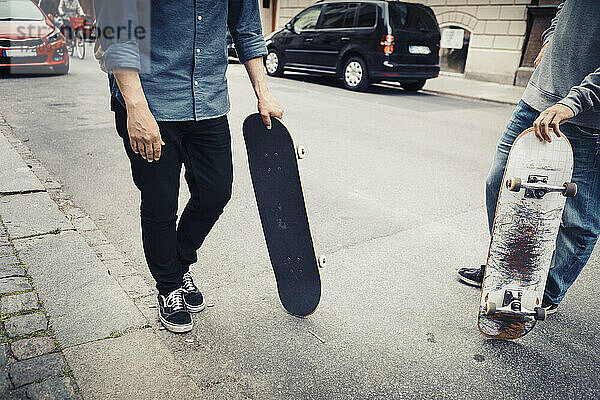 Niedriger Ausschnitt von männlichen Freunden mit Skateboard auf der Straße