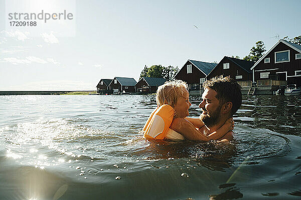 Seitenansicht der lächelnden Tochter mit Vater im See während der Ferien