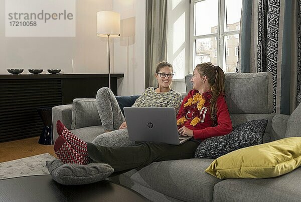 Zwei junge Frauen sitzen mit dem Laptop auf einem Sofa