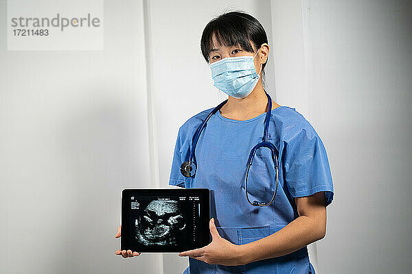 Eine Ärztin hält einen Bildschirm mit einem Ultraschallbild des Fötus