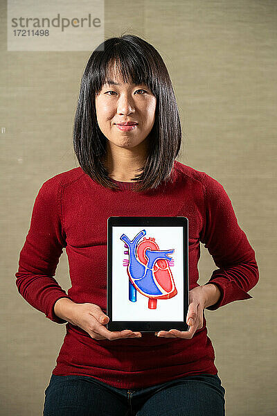 Frau hält einen Bildschirm mit einem Herzausschnitt