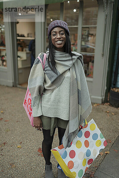 Porträt glückliche junge Frau mit Einkaufstasche auf dem Bürgersteig