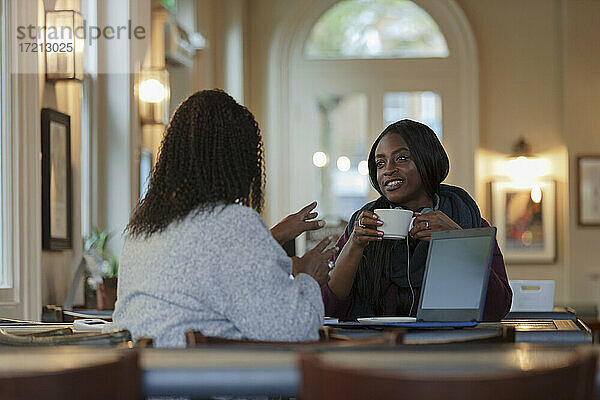 Geschäftsfrauen reden und trinken Kaffee am Laptop im Café