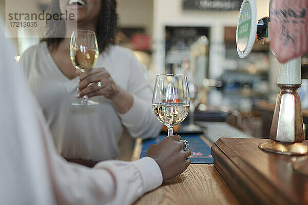 Frauen genießen Weißwein am Tresen in einer Kneipe