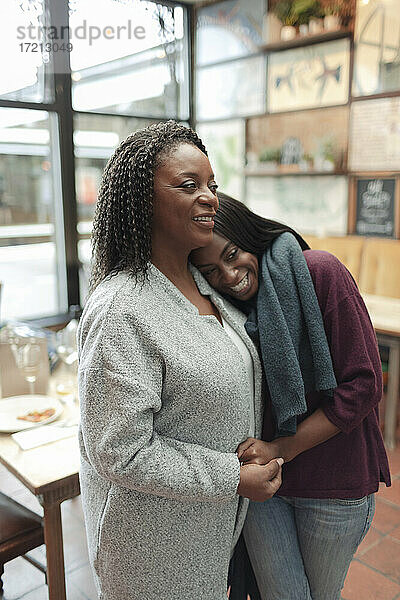 Zärtliche Mutter und Tochter umarmen im Café