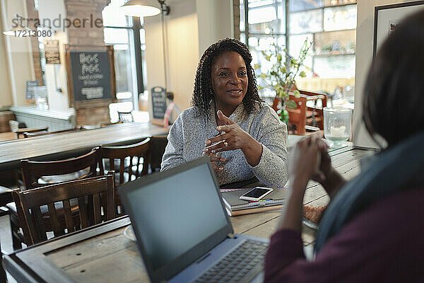 Geschäftsfrauen treffen und sprechen am Laptop im Café