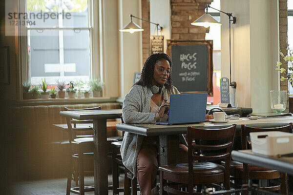 Frau arbeitet am Laptop im Café Tisch