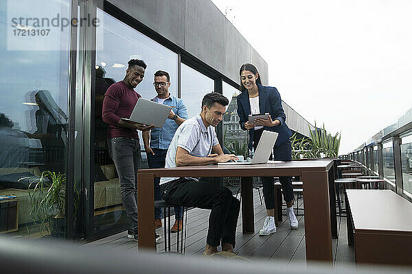 Geschäftsleute arbeiten mit Laptops und digitalem Tablet auf dem Balkon
