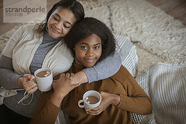 Porträt liebevolle Mutter und Tochter kuscheln mit heißem Kakao