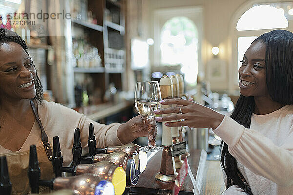 Freundlicher Barkeeper serviert Weißwein an Frau im Pub