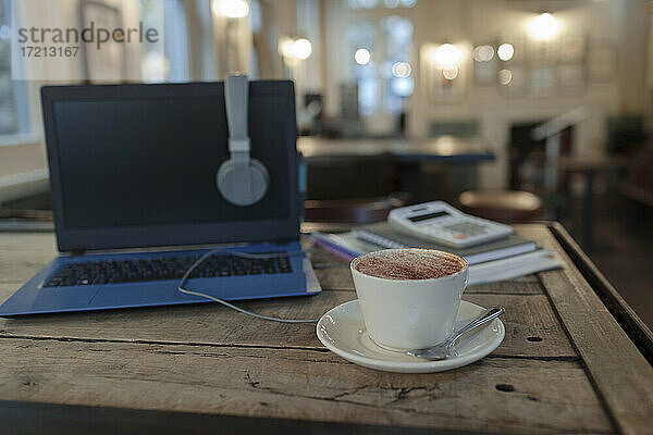 Cappuccino auf dem Tisch neben dem Laptop im Cafe