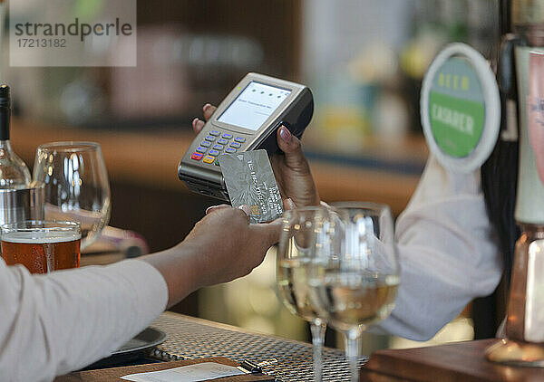 Close up Kunde zahlt Barkeeper mit Smartcard in Bar