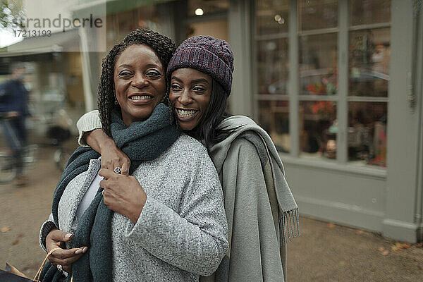 Porträt glückliche Mutter und Tochter umarmen auf dem Bürgersteig