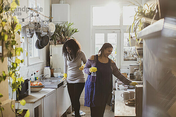 Mutter und Tochter in Gummihandschuhen beim Reinigen der Küche