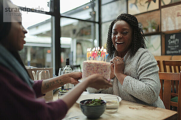 Glückliche Mutter und Tochter feiern Geburtstag mit Kuchen im Cafe