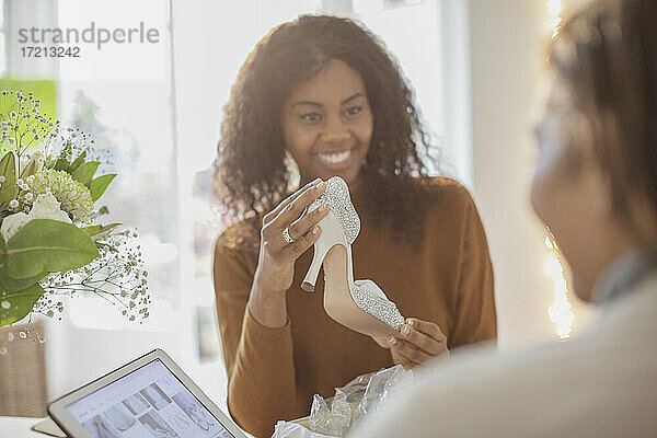 Glückliche junge Frau mit Hochzeitsschuhen Online-Shopping mit Mutter