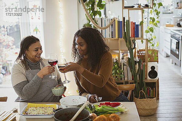 Mutter und Tochter kochen und trinken Wein in der Küche