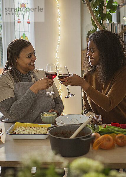 Mutter und Tochter kochen und trinken Wein zu Hause
