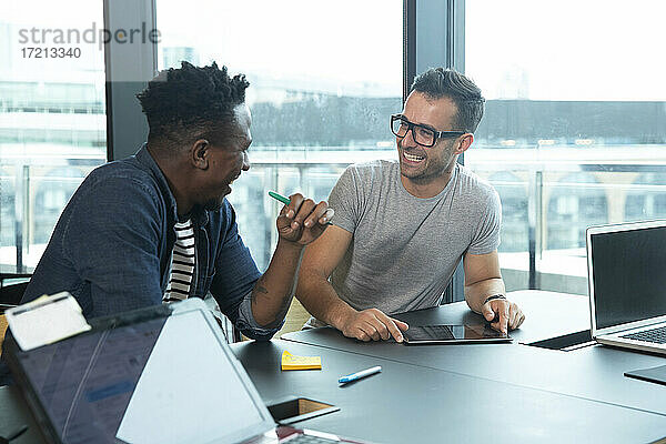 Glückliche Geschäftsleute mit digitalem Tablet Meeting im Büro