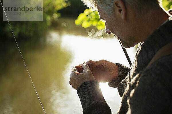 Close up Mann bereitet Fliegenfischen Fliege am sonnigen Fluss