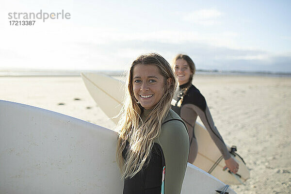 Porträt glücklich junge weibliche Surfer mit Surfbrett auf sonnigen Strand