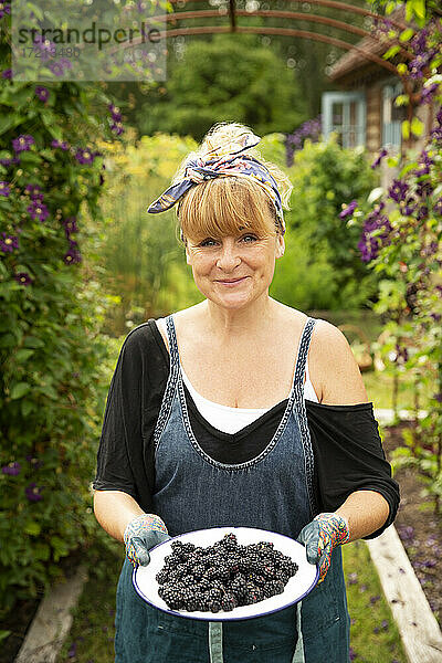 Portrait stolze Frau mit frisch geernteten Brombeeren im Garten