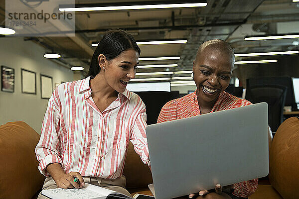 Glückliche Geschäftsfrau arbeitet am Laptop im Büro
