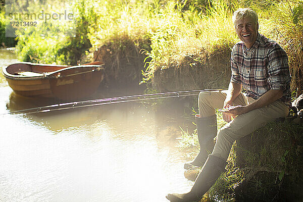 Portrait glücklicher Mann Fliegenfischen am sonnigen Flussufer