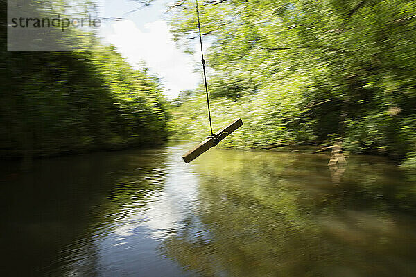 Seilschaukel schwingt über grünem Fluss