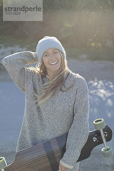 Porträt glückliche junge Frau mit Skateboard