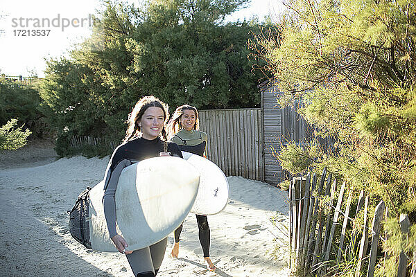 Junge weibliche Surfer mit Surfbrettern auf sonnigen Strand Weg